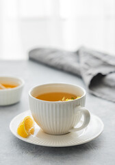 Cup of herbal tea with lemon and honey on table against window background