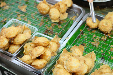 Thai coconut rice pancakes (kanom krok) in a clear plastic box at a street stall in the market