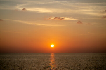 Stunning sunset over the Andaman Sea in Phuket, Thailand, with vibrant hues of orange, pink, and purple reflecting on the calm waters