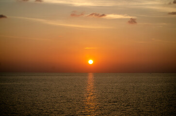 Naklejka premium Stunning sunset over the Andaman Sea in Phuket, Thailand, with vibrant hues of orange, pink, and purple reflecting on the calm waters