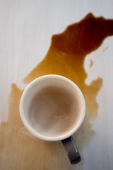 Coffee cup and spilled coffee on the table in the morning