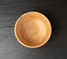 Empty wood bowl on black tabletop, light wooden plate, moody dish mockup, kitchen banner