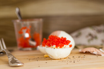 red caviar and boiled eggs on a wooden board