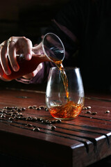 pouring black coffee into clear glass 