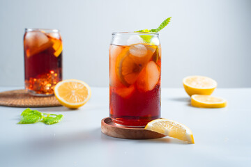 Iced tea with lemon and ice in a tall glass on a white background. The concept of a refreshing drink or lemonade on a hot summer day. Front view and copy space.