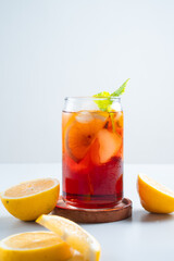 Iced tea with lemon and ice in a tall glass on a white background. The concept of a refreshing drink or lemonade on a hot summer day. Front view and copy space.
