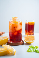 Iced tea with lemon and ice in a tall glass on a white background. The concept of a refreshing drink or lemonade on a hot summer day. Front view and copy space.
