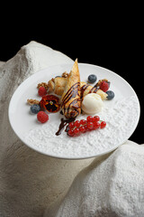 Chocolate dessert with red berries and cream on elegant white plate