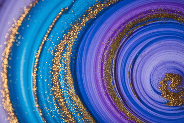 Colorful liquid paint abstract background blue and purple acrylic paints with golden glitter blending texture