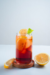 Iced tea with lemon and ice in a tall glass on a white background. The concept of a refreshing drink or lemonade on a hot summer day. Front view and copy space.