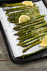 Grilled green asparagus with lemon on baking tray and hard cheese