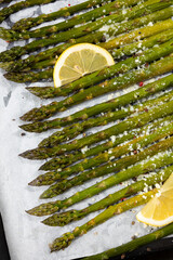 Grilled asparagus with lemon on baking tray and hard cheese