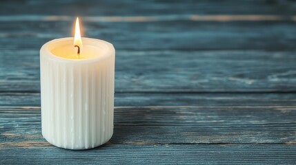 A white pillar candle burning on a rustic blue wooden surface.