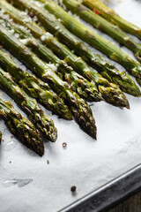 Close up of grilled green asparagus on baking tray and hard cheese