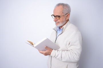 Side view of a senior mature man reading a book standing isolated over grey background.