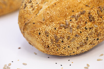 Whole artisan wheat bread with sesame and sunflower seeds on white background