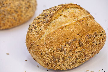 Whole artisan wheat bread with sesame and sunflower seeds on white background