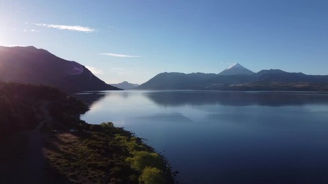 aereal pan shot of stunning lighting and scenario in Huechulafquen Lake in Argentina with Lanin Volcano nexto to it