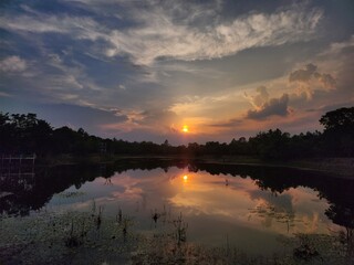 Stunning sunset over a tranquil lake with vivid reflections and dramatic clouds. Ideal for backgrounds, nature themes, travel, and inspirational content. Perfect peaceful nature scene.