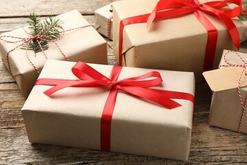 Many gifts wrapped in kraft paper with bow on wooden background, closeup
