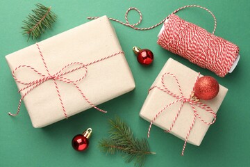 Gifts wrapped in kraft paper and Christmas decor on green background, flat lay
