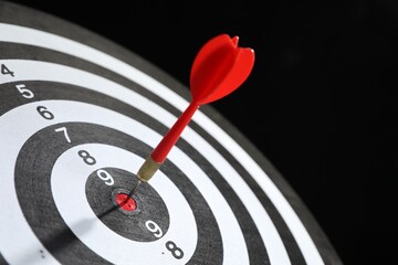 Targeting. Dart board with arrow on black background, closeup