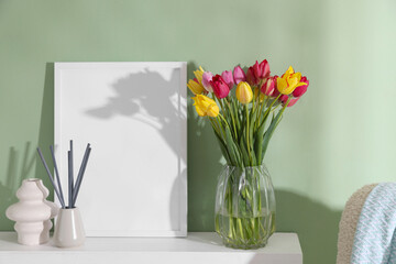 Bouquet of beautiful tulips and decor on table near color wall