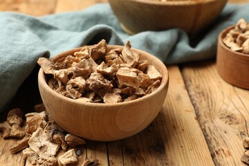 Pieces of dry chicory roots in bowl on wooden table, closeup