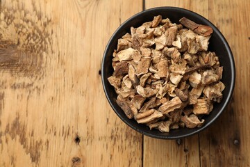Pieces of dry chicory roots in bowl on wooden table, top view. Space for text