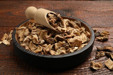 Pieces of dry chicory roots in bowl and scoop on wooden table, closeup