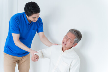 Obraz premium 肩が痛い高齢者男性とスタッフ
