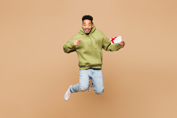 Full body young man of African American ethnicity wears green hoodie casual clothes jump high hold...