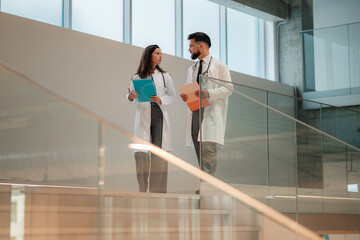 Doctors discussing patient chart walking in hospital corridor