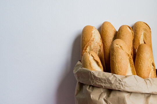 Freshly baked baguettes in a paper bag against a white background