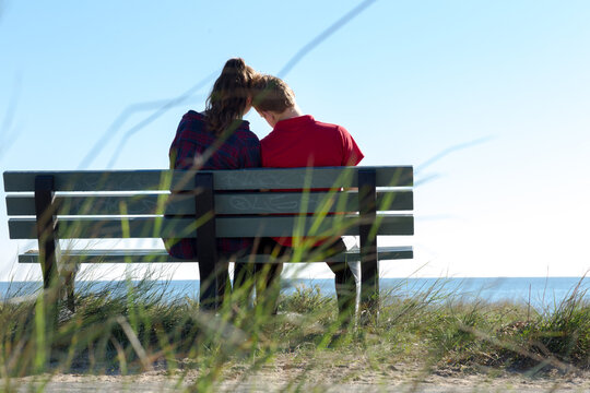 Couple seen from behind close together on park bench