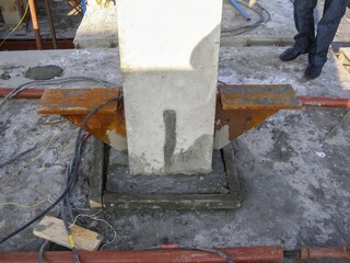 Concrete pillar base construction, showing support brackets, and groundwork, under development.