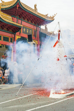 A cloud of smoke rising from a string of firecrackers going off in front of a Chinese building