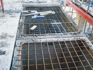 An overhead view highlights metal grating over concrete pits within a construction zone.