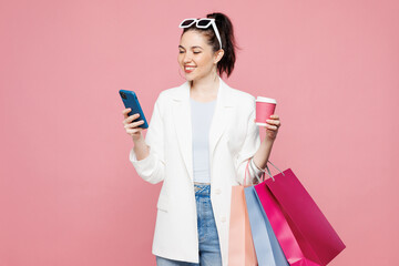 Young fun woman wear white clothes hold in hand paper package bags after shopping use mobile cell...