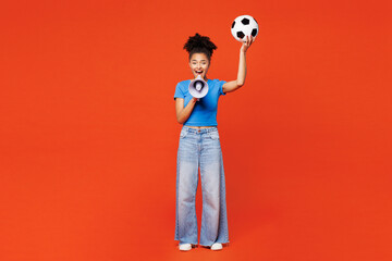 Fototapeta premium Full body young happy woman fan wear blue t-shirt cheer up support football sport team hold soccer ball scream in megaphone announces sale watch tv live stream isolated on plain red orange background.