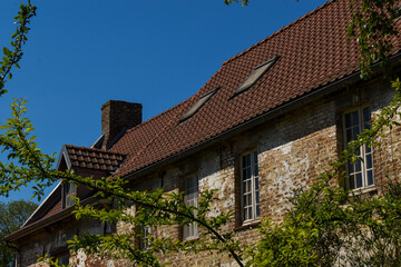 Façade et toit d'une vieille maison entourée par la végétation du verger
