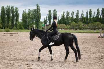 Beautiful blonde learns to ride a horse. Summer sunny day.