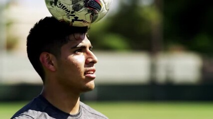Man is juggling soccer ball with his head. Slow motion footage - Powered by Adobe
