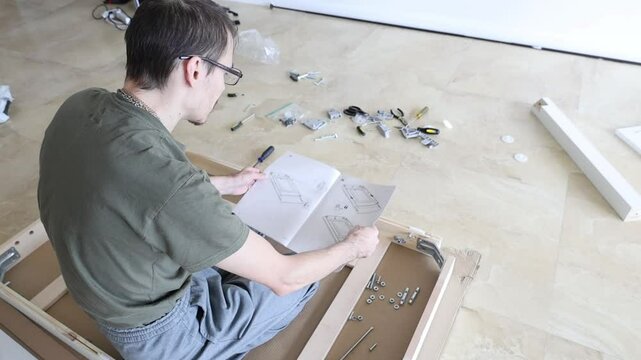 Male preparing for furniture assembly with instruction sheet