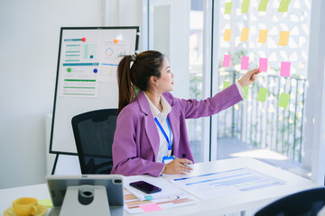 Happy attractive Asian businesswoman working on laptop and holding coffee cup with smile in Modern office or living room with copy space,E-commerce,internet technology, startup small business concept