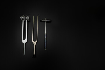 tuning fork C 128 on a black background with gradation and otorhinoscope and neurological hammer