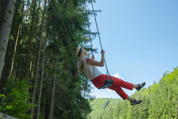 Woman Enjoying Nature on a Swing. Embraces lightness and freedom, surrounded by fresh air and greenery. Relaxation, happiness, connection to nature	