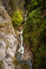 Dramatic Narrow Canyon In Leutaschklamm Gorge: Crystal-Clear Turquoise Mountain Stream Winding Through Steep Rocky Cliffs Surrounded By Moss-Covered Walls And Lush Greenery In Tyrol, Austria