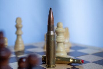 A vertical bullet placed among chess pieces on a wooden board creates a dramatic visual metaphor,...