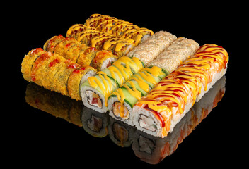 Sushi roll platter with sauces and sesame on black reflective surface